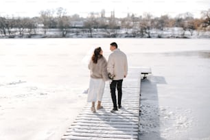 a man and a woman standing on a snow covered dock
