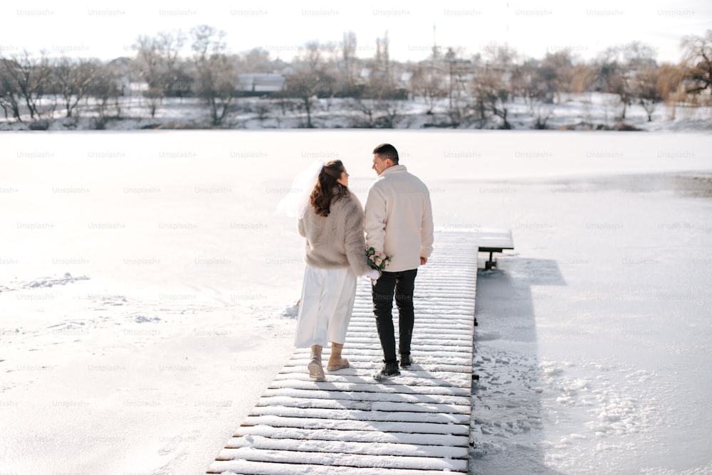 a man and a woman standing on a snow covered dock