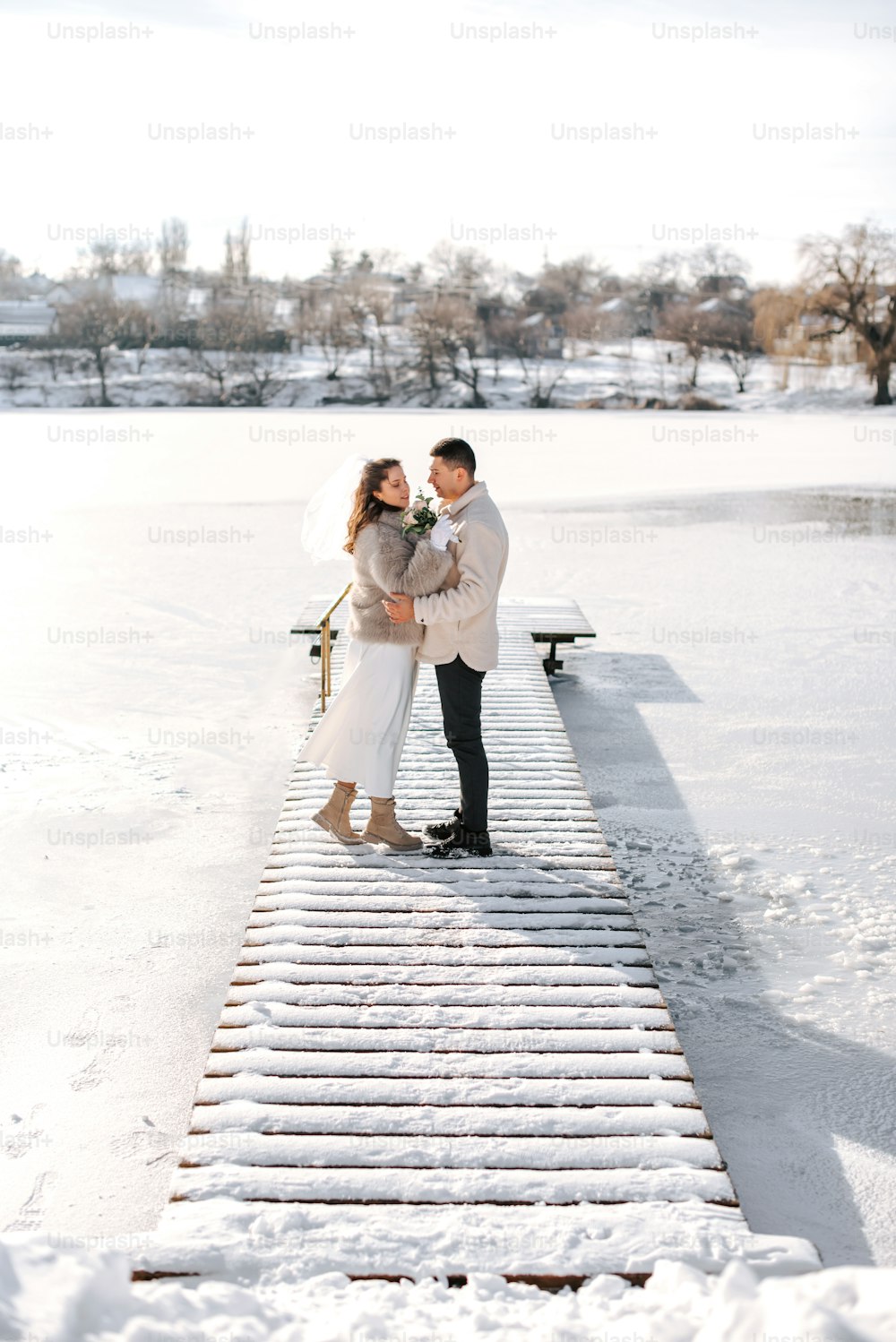 a man and a woman standing on a snow covered pier