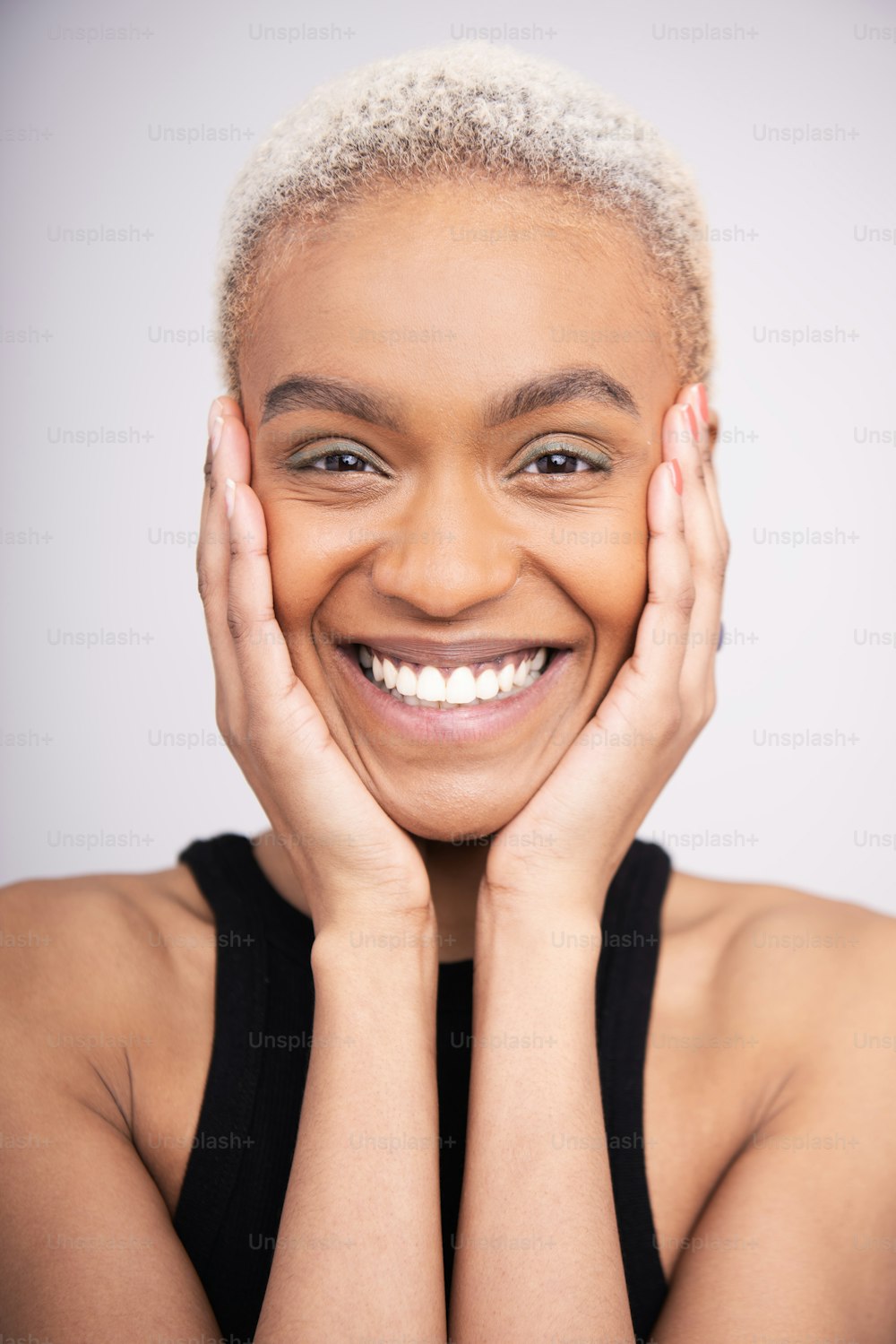 a woman smiling with her hands on her face