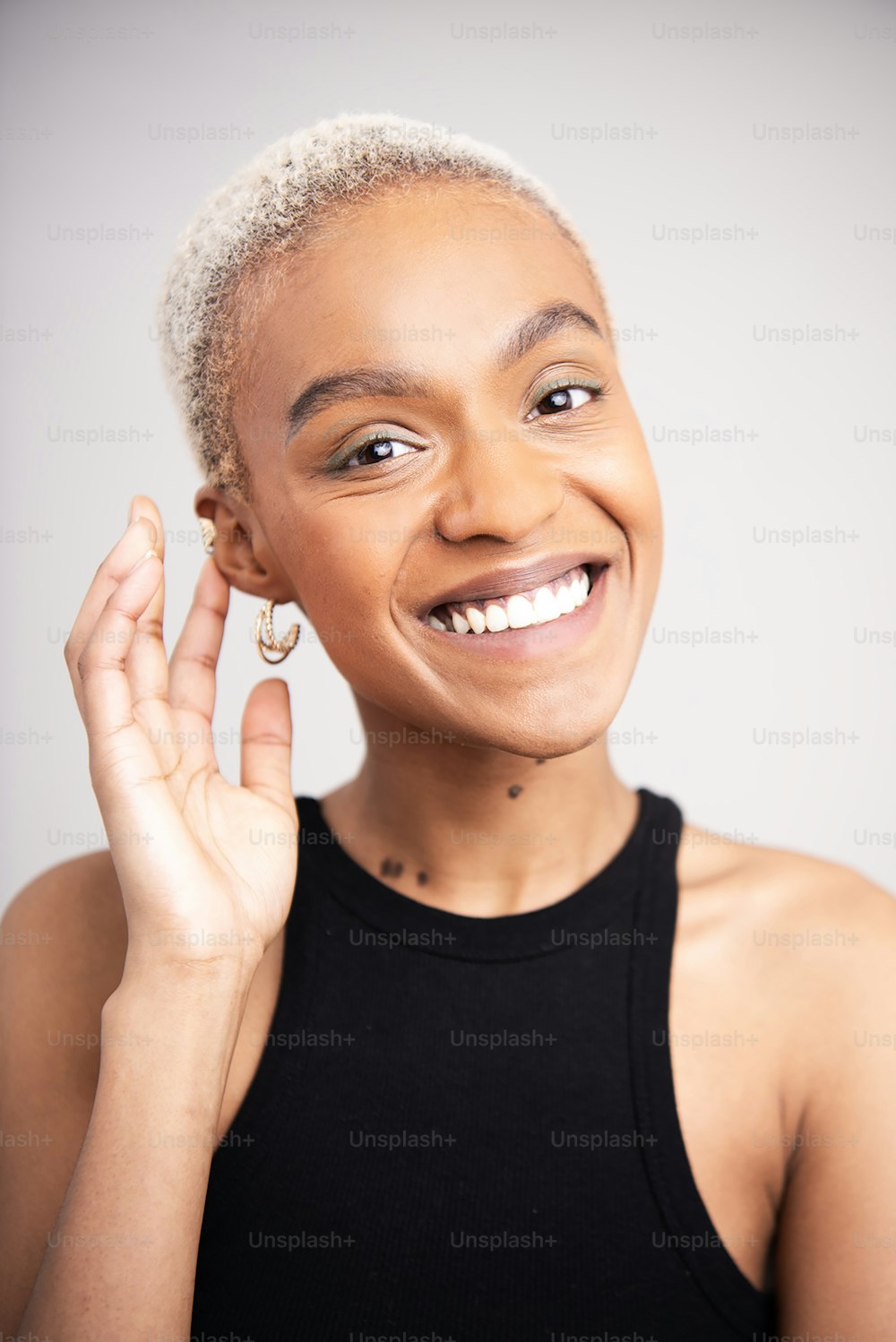 a woman smiling and holding her hand up to her ear