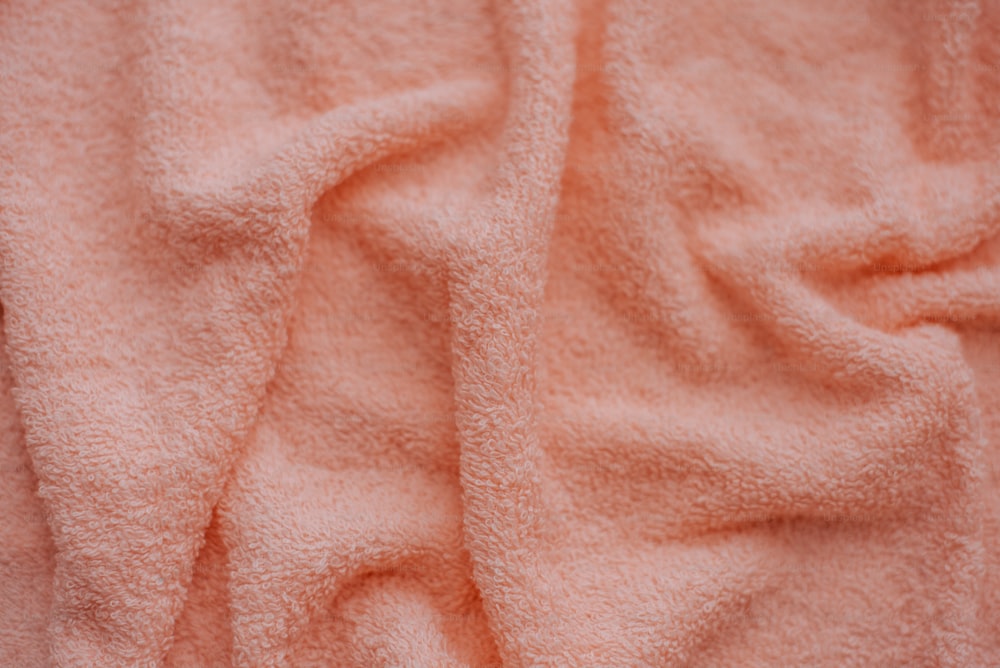 a close up of a pink towel on a bed