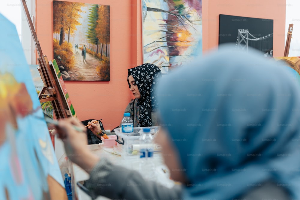 a woman in a hijab painting on a canvas