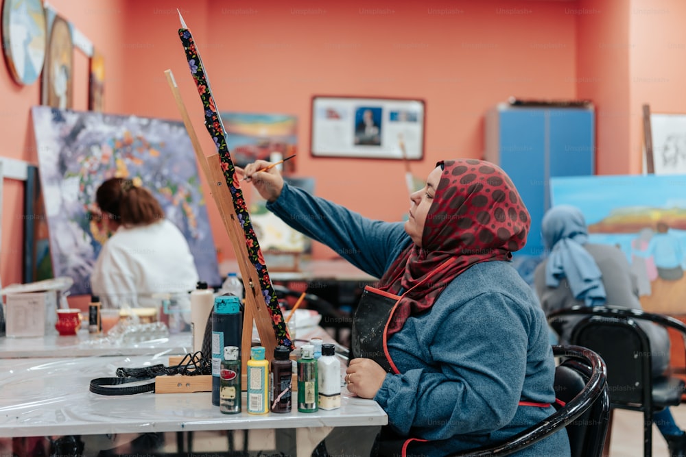 a woman sitting in a chair painting a picture