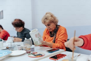 a group of women sitting at a table with paint brushes