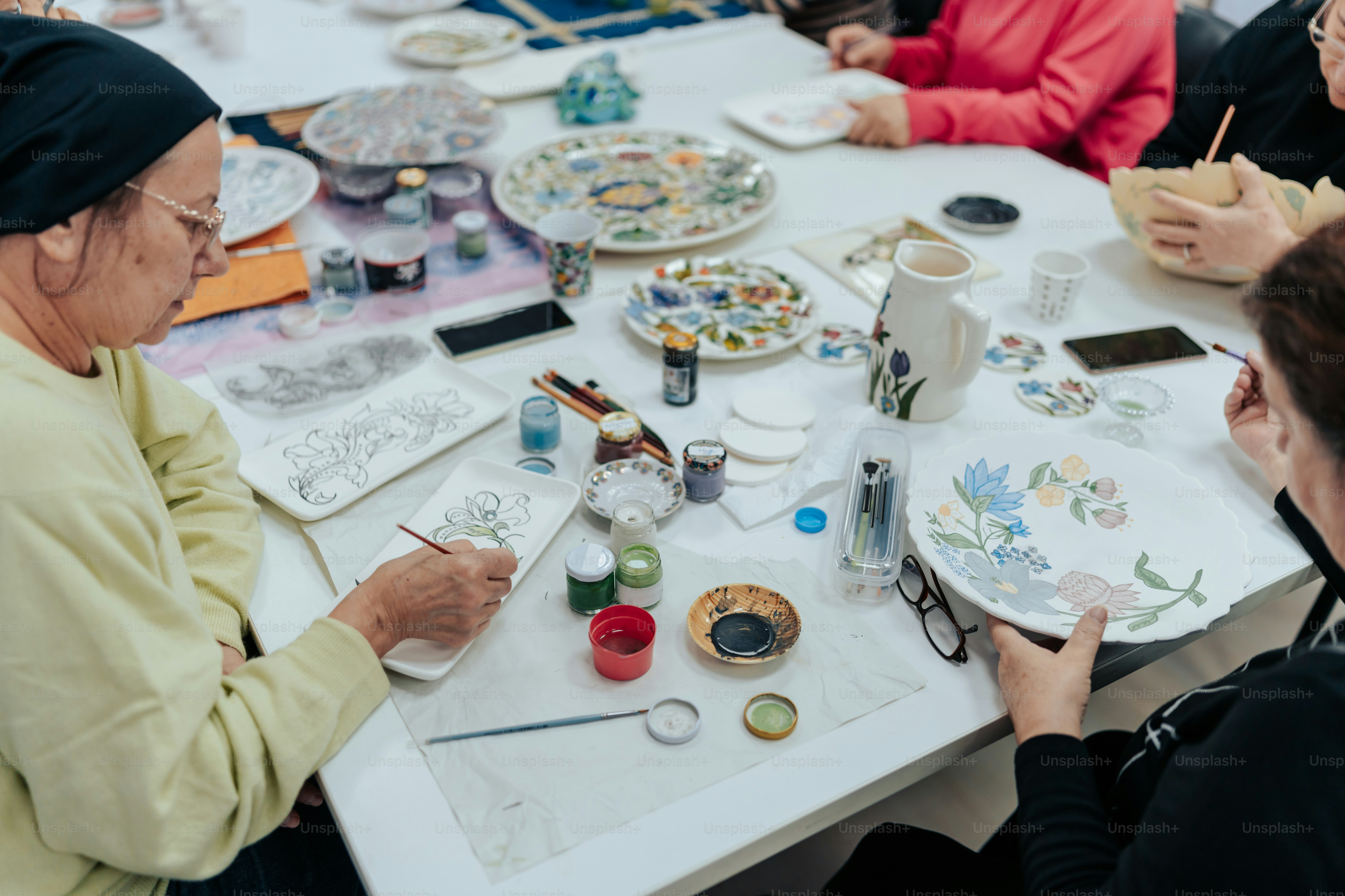 a group of women sitting around a table painting