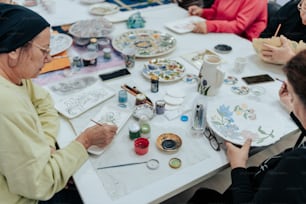 a group of women sitting around a table painting