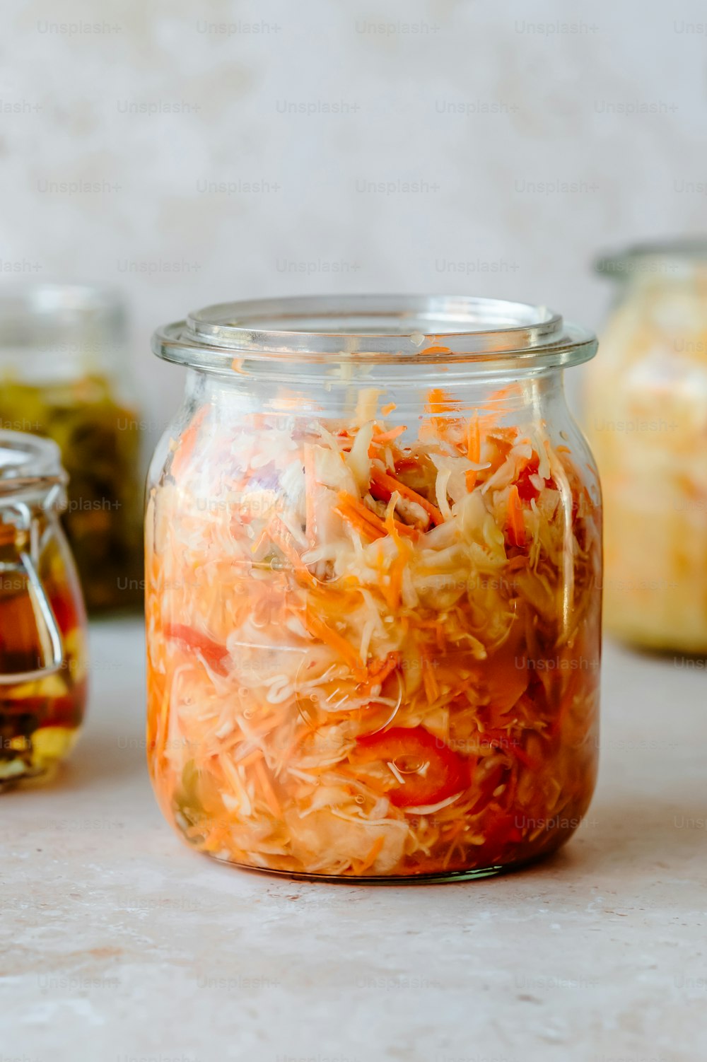 a jar filled with shredded carrots next to jars of pickles