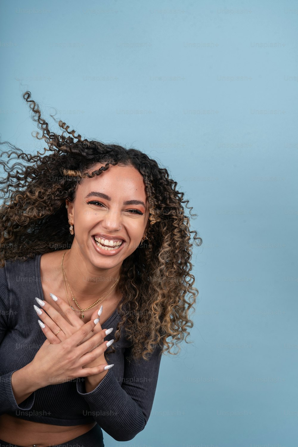 a woman with curly hair smiling and holding her hands together