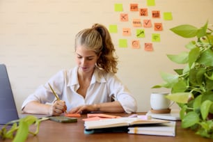une femme assise à un bureau écrivant sur un morceau de papier