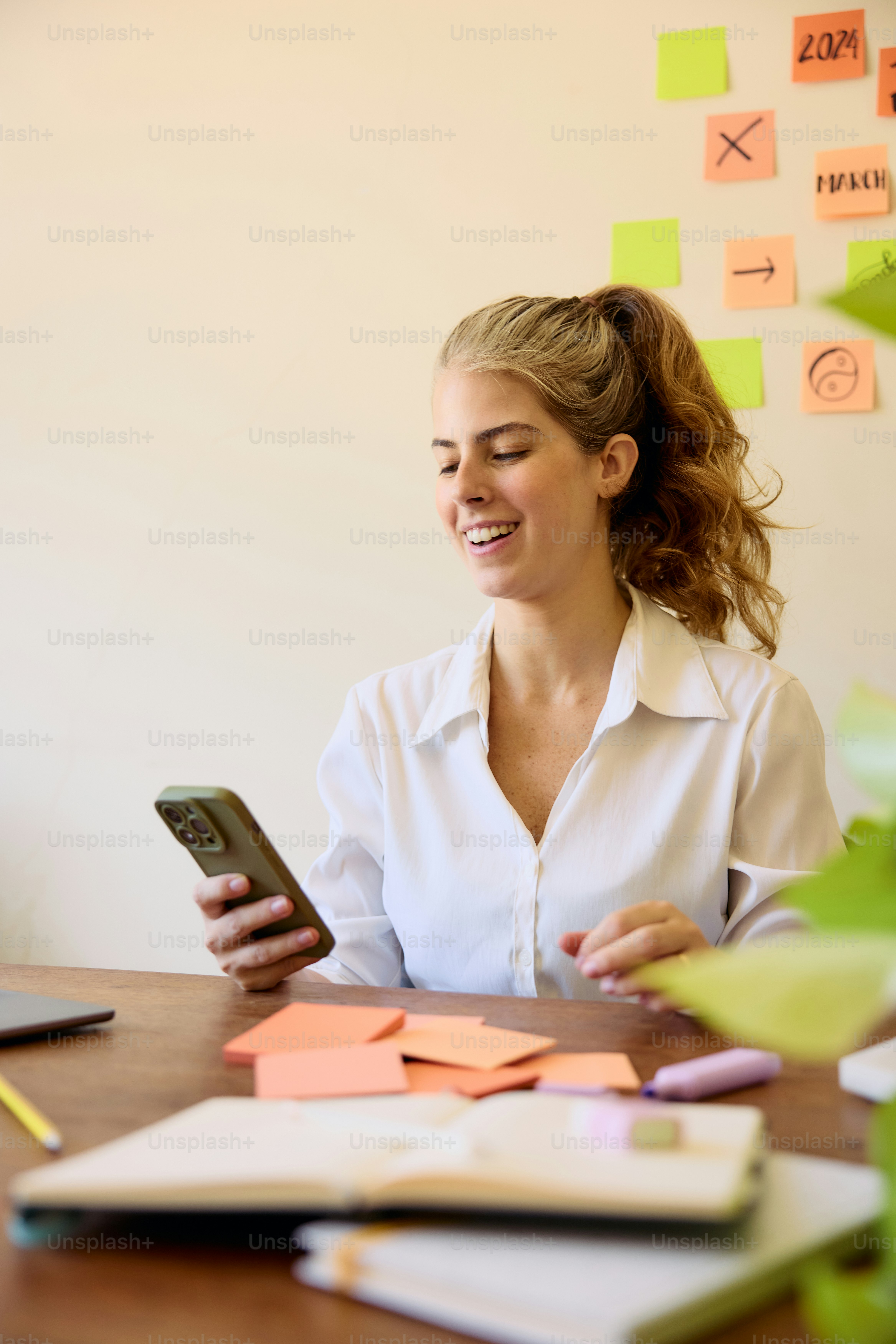 una mujer sentada en una mesa con un teléfono celular