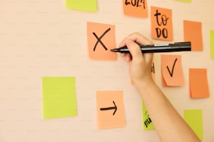 a person writing on a wall with post it notes