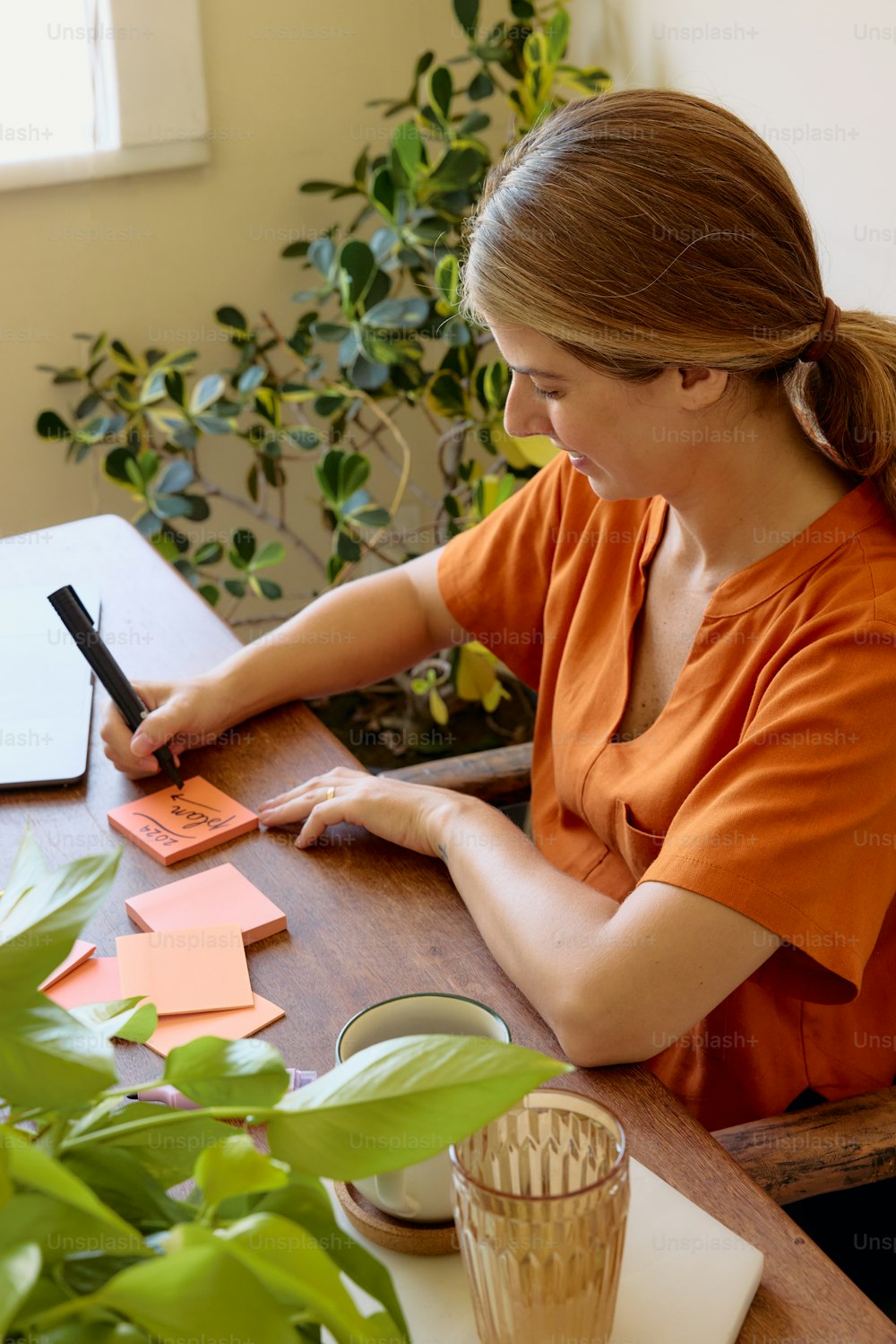 una mujer sentada en una mesa escribiendo en un pedazo de papel