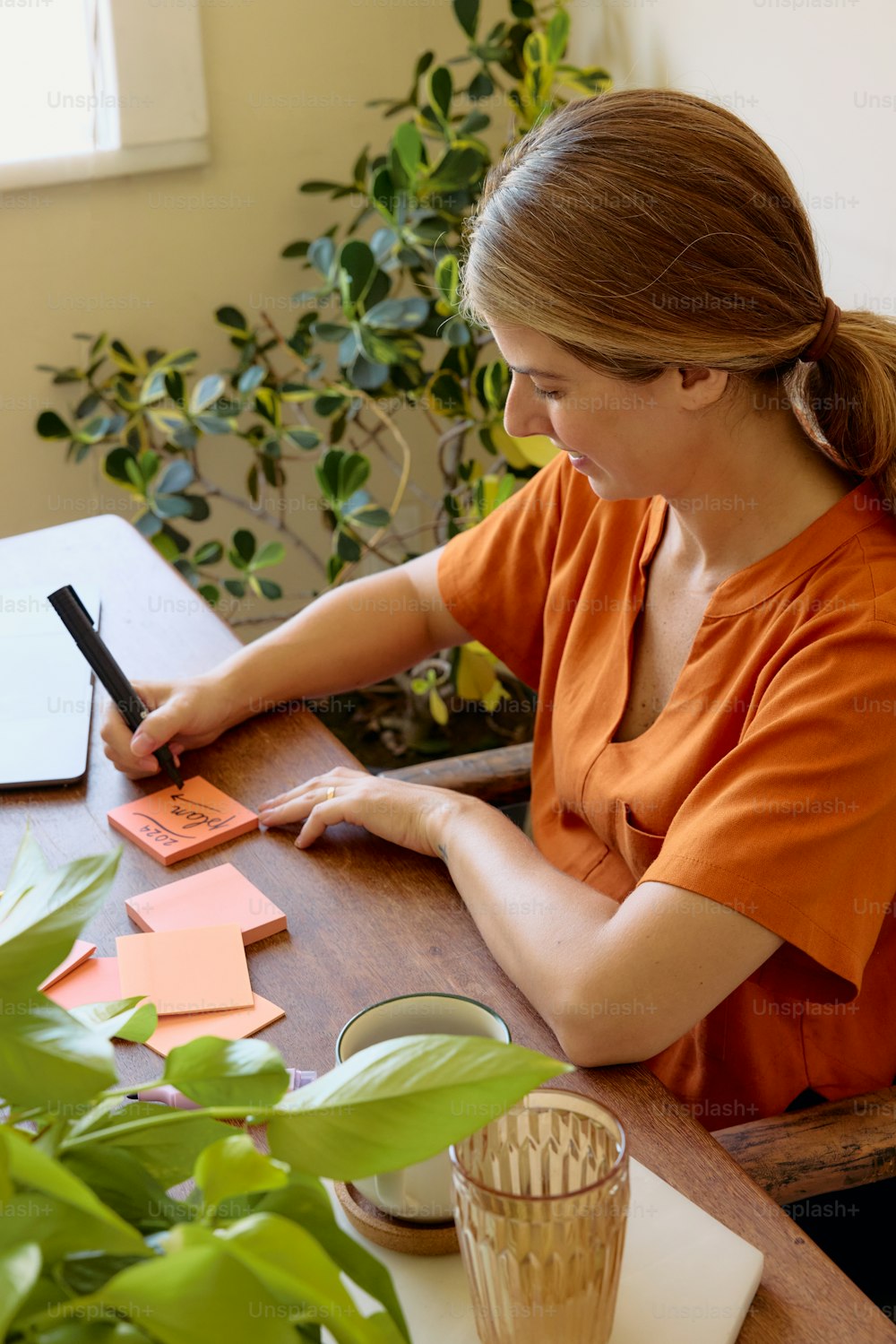 a woman sitting at a table writing on a piece of paper