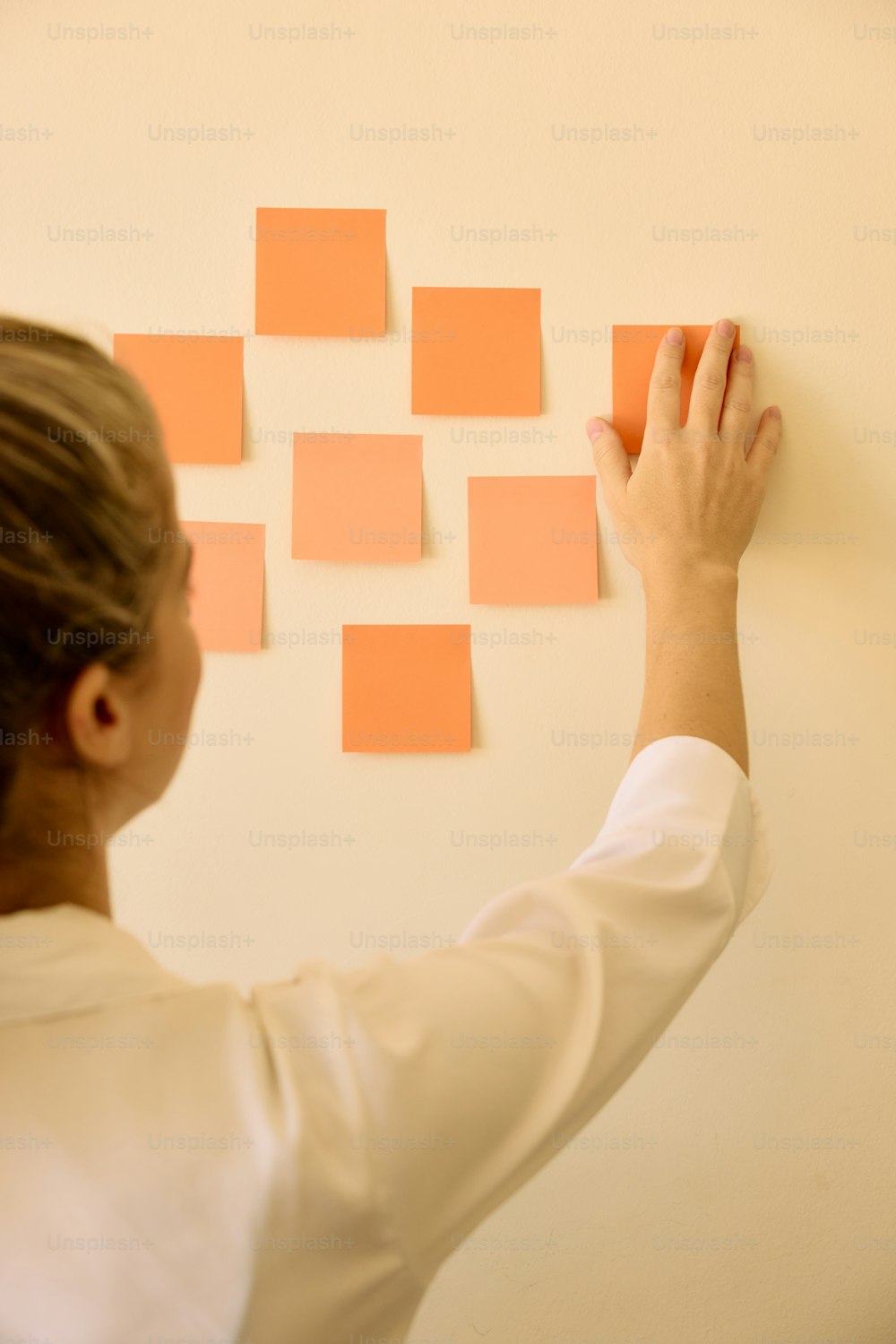 a woman is placing orange squares on a wall