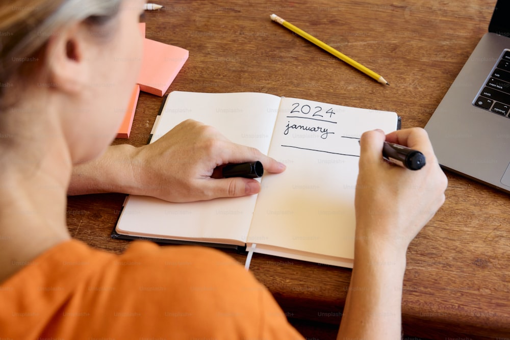 uma mulher está escrevendo em um caderno com uma caneta