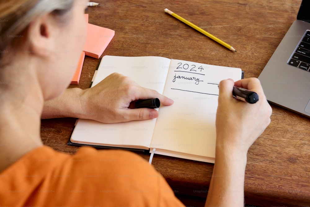 a woman is writing on a notebook with a pen