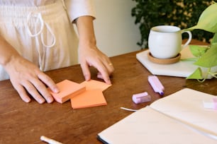 Eine Frau schneidet auf einem Tisch Papierschnipsel aus