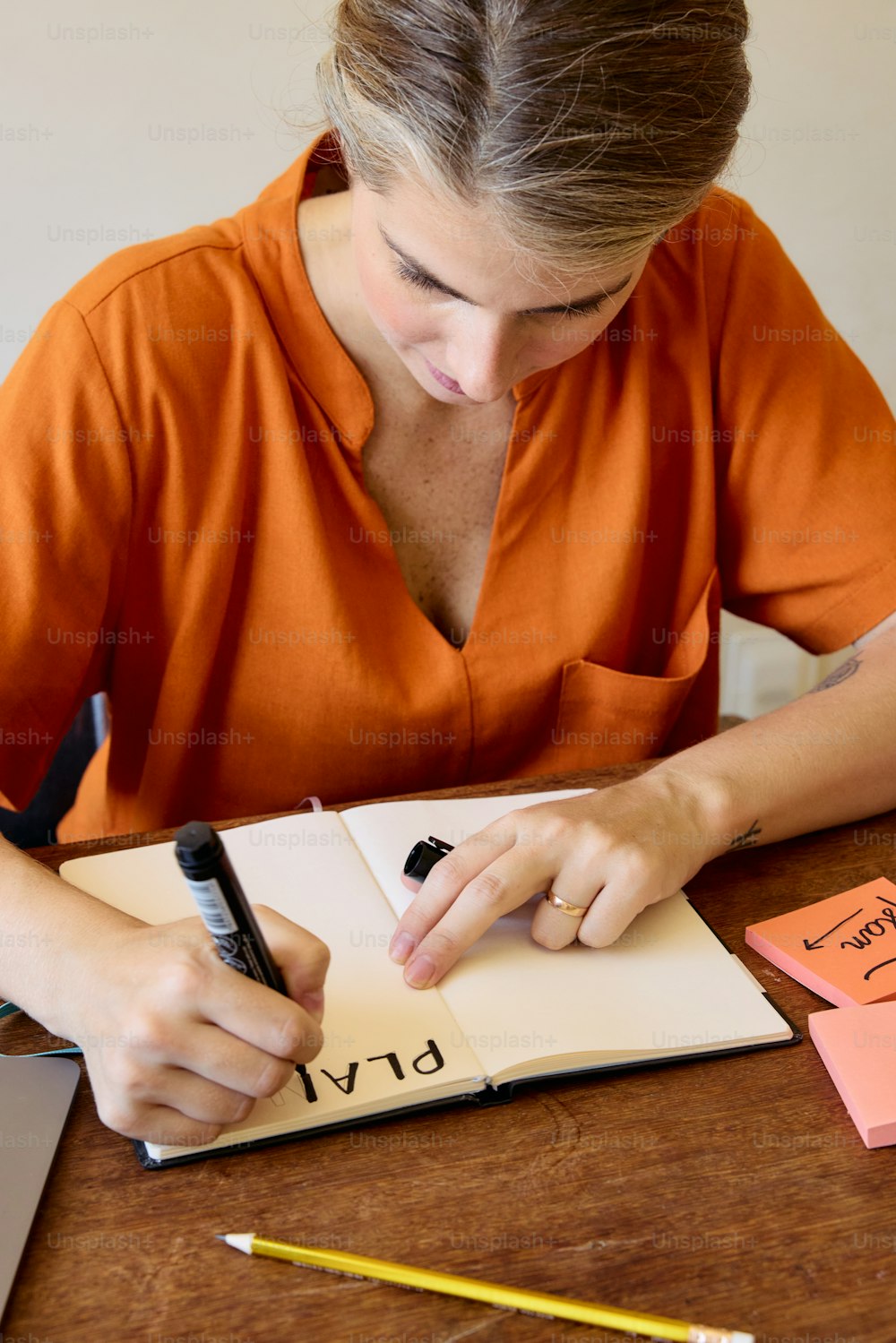 uma mulher sentada em uma mesa escrevendo em um caderno