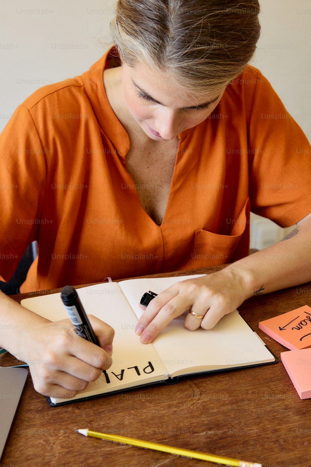 a woman sitting at a table writing on a notebook