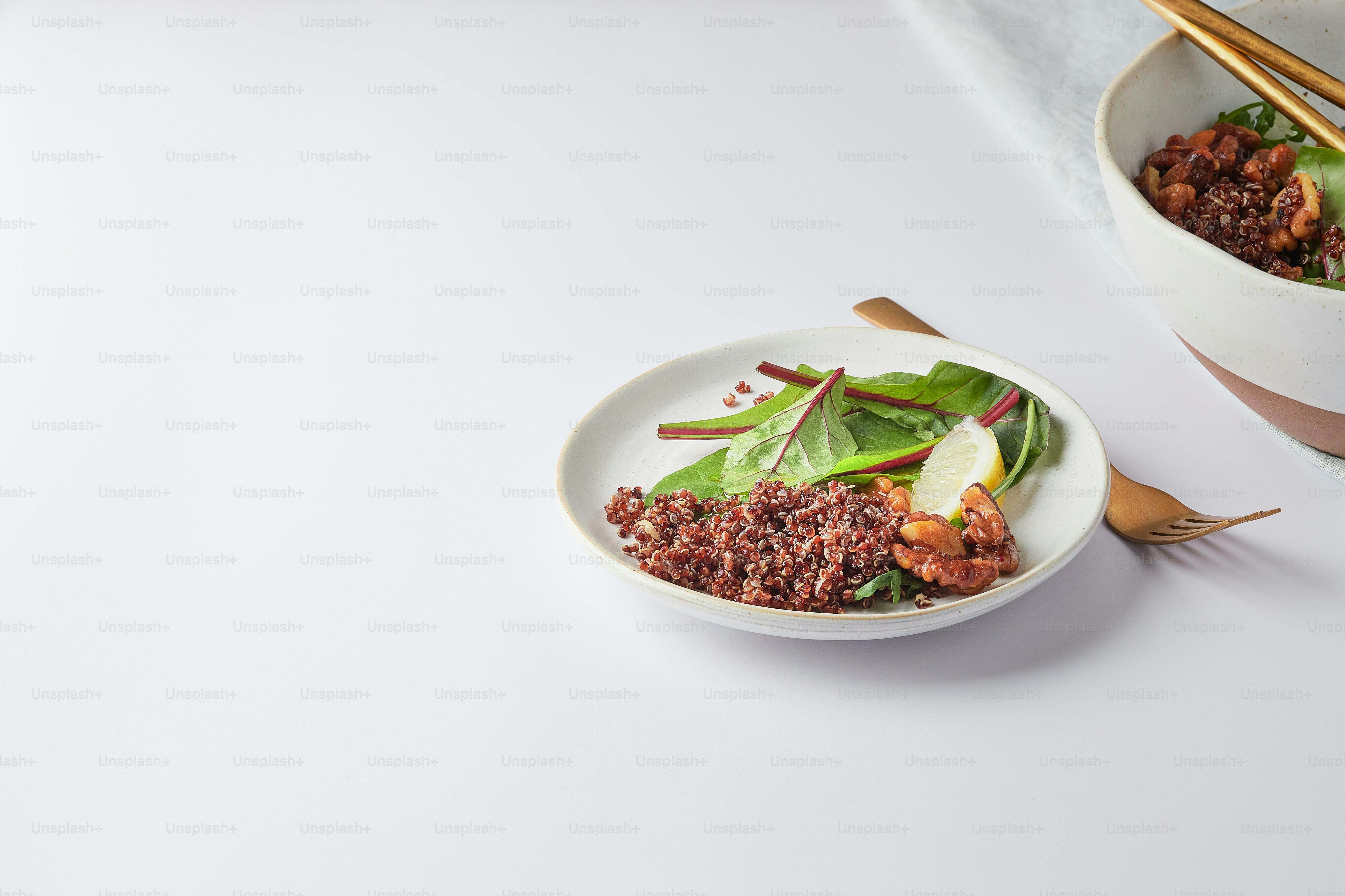 a white plate topped with a salad next to a bowl of salad