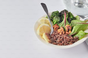 a bowl of food with broccoli, spinach, and lemon wedges
