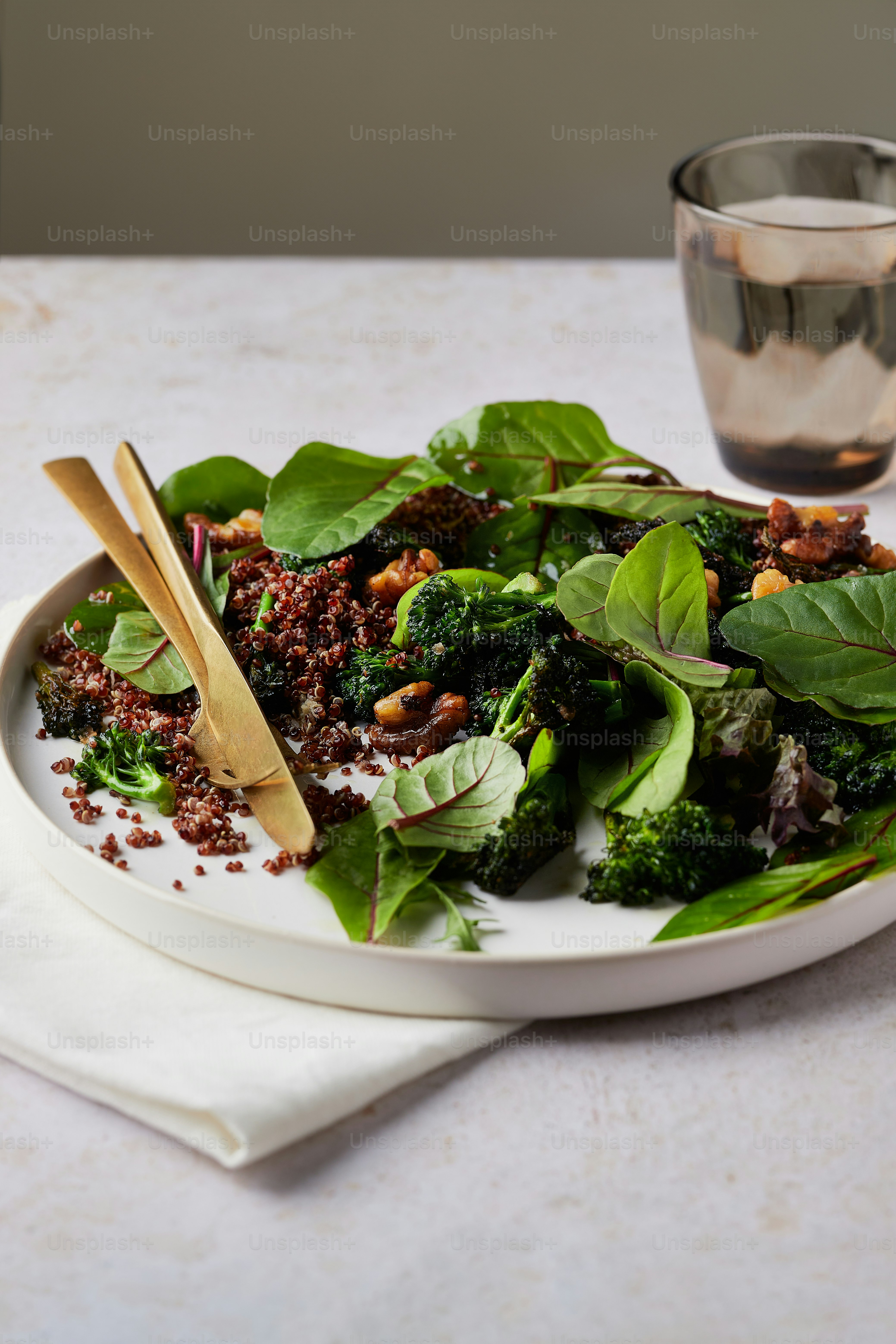 ein weißer Teller mit Grünzeug und einem Holzlöffel