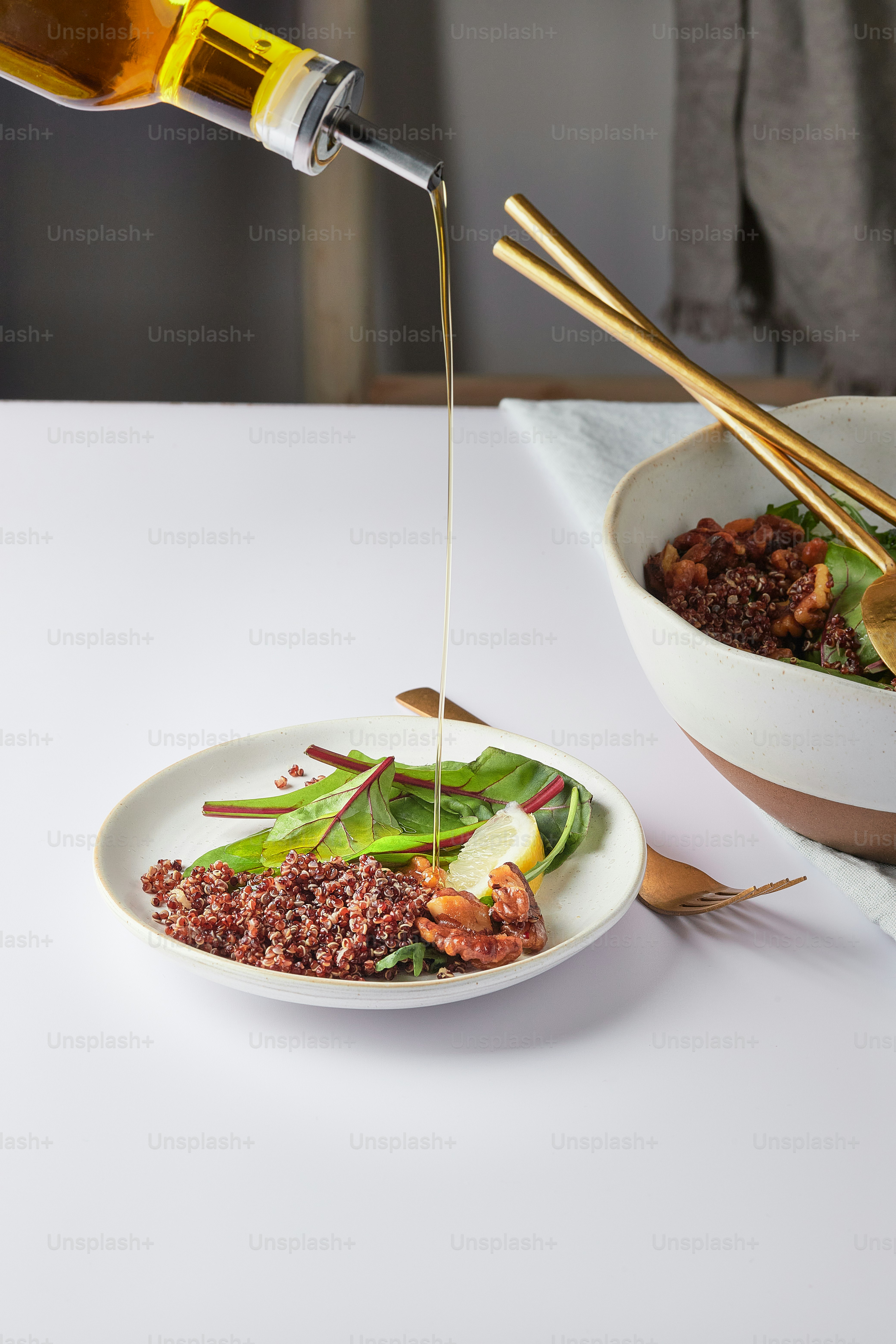 a white plate topped with a salad next to a bowl of salad