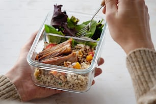 a person holding a plastic container filled with food