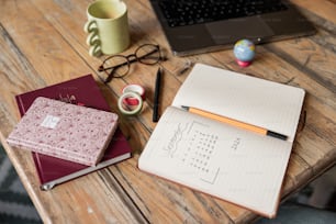 a wooden table topped with notebooks and a laptop computer