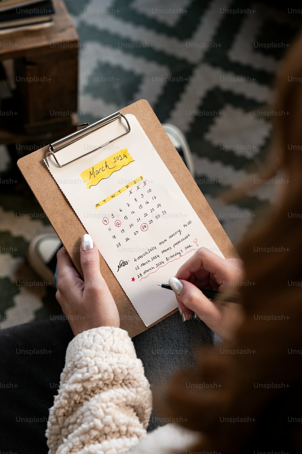 a woman is holding a clipboard with a calendar on it