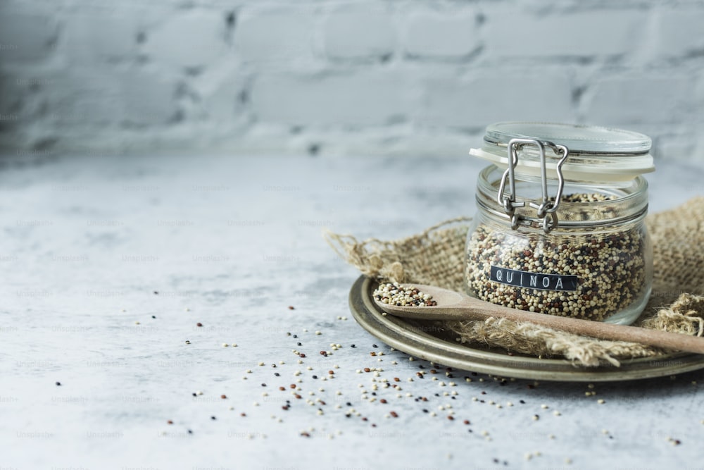 a glass jar filled with bird seed next to a wooden spoon