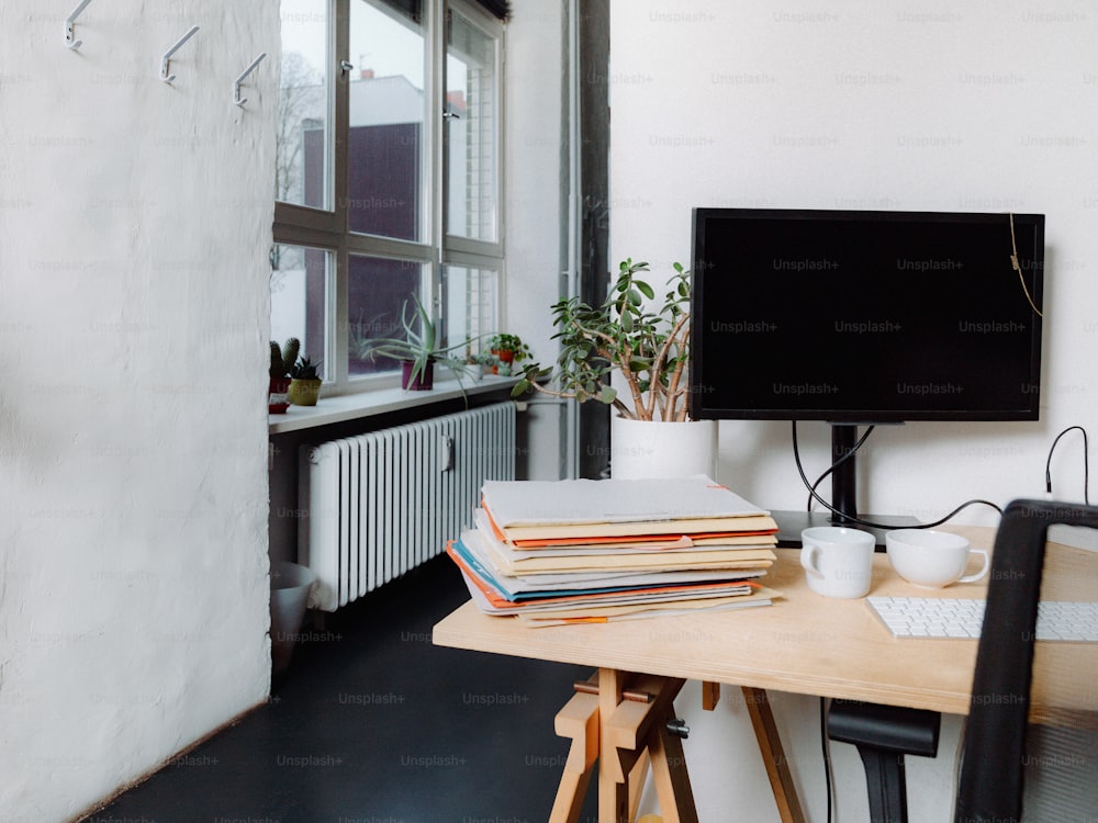 a desk with a monitor, keyboard and a stack of books