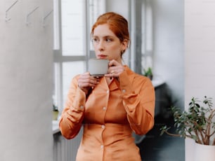 a woman in an orange shirt holding a cup of coffee