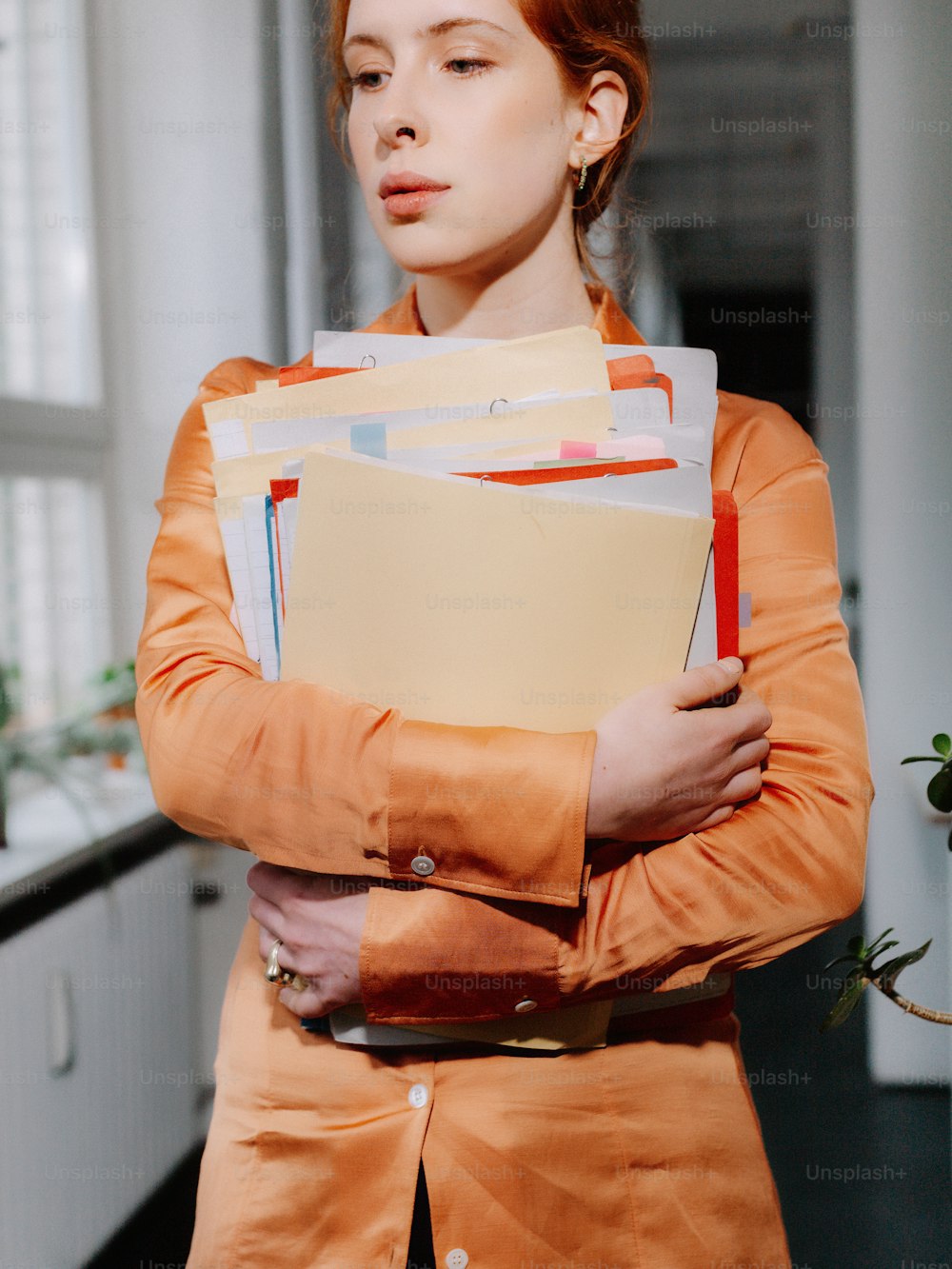 a woman in an orange dress holding a folder