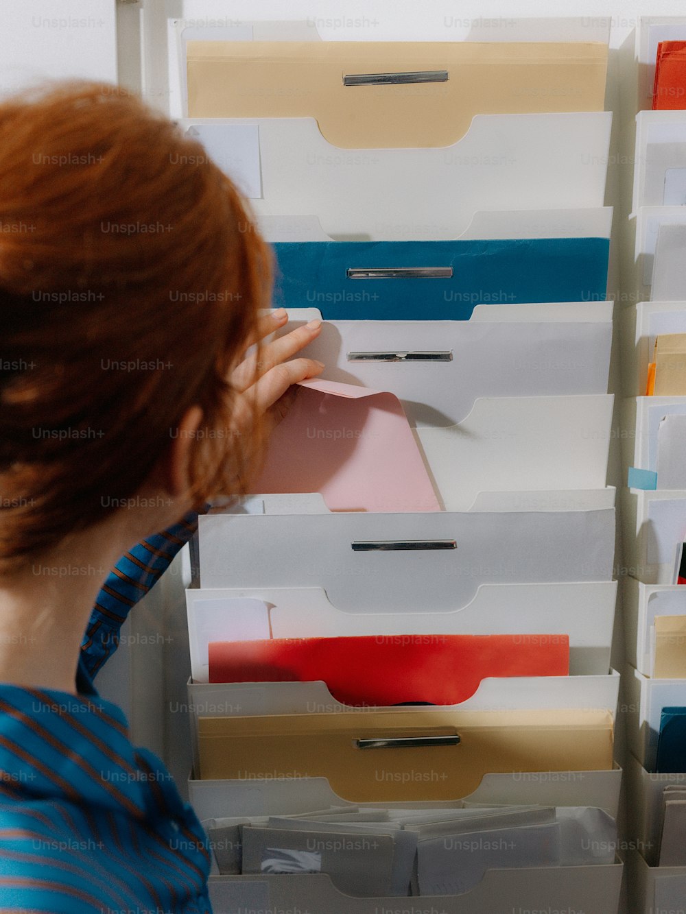 a woman looking at a stack of file cabinets