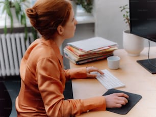 une femme assise à un bureau avec un clavier et une souris