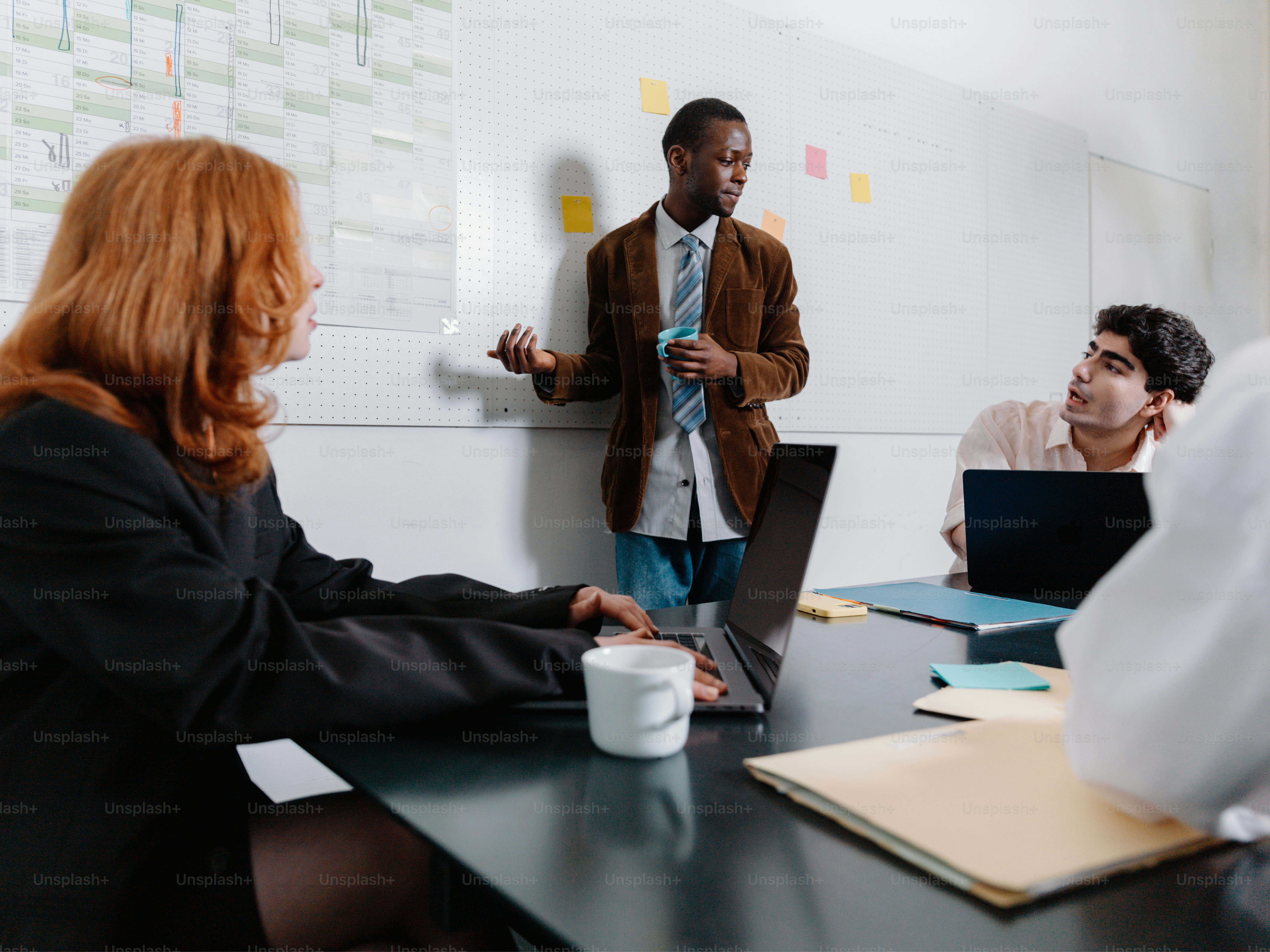 a group of people sitting around a table with laptops