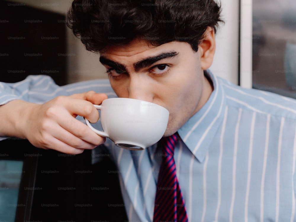 un hombre con camisa y corbata bebiendo de una taza