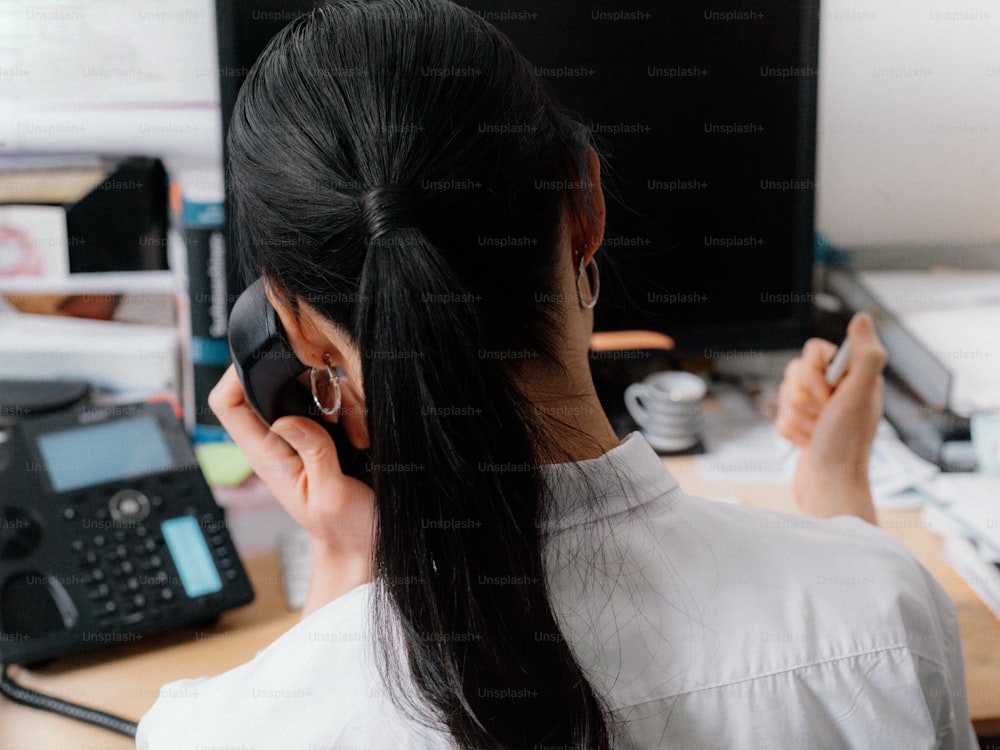 une femme assise à un bureau en train de parler au téléphone portable