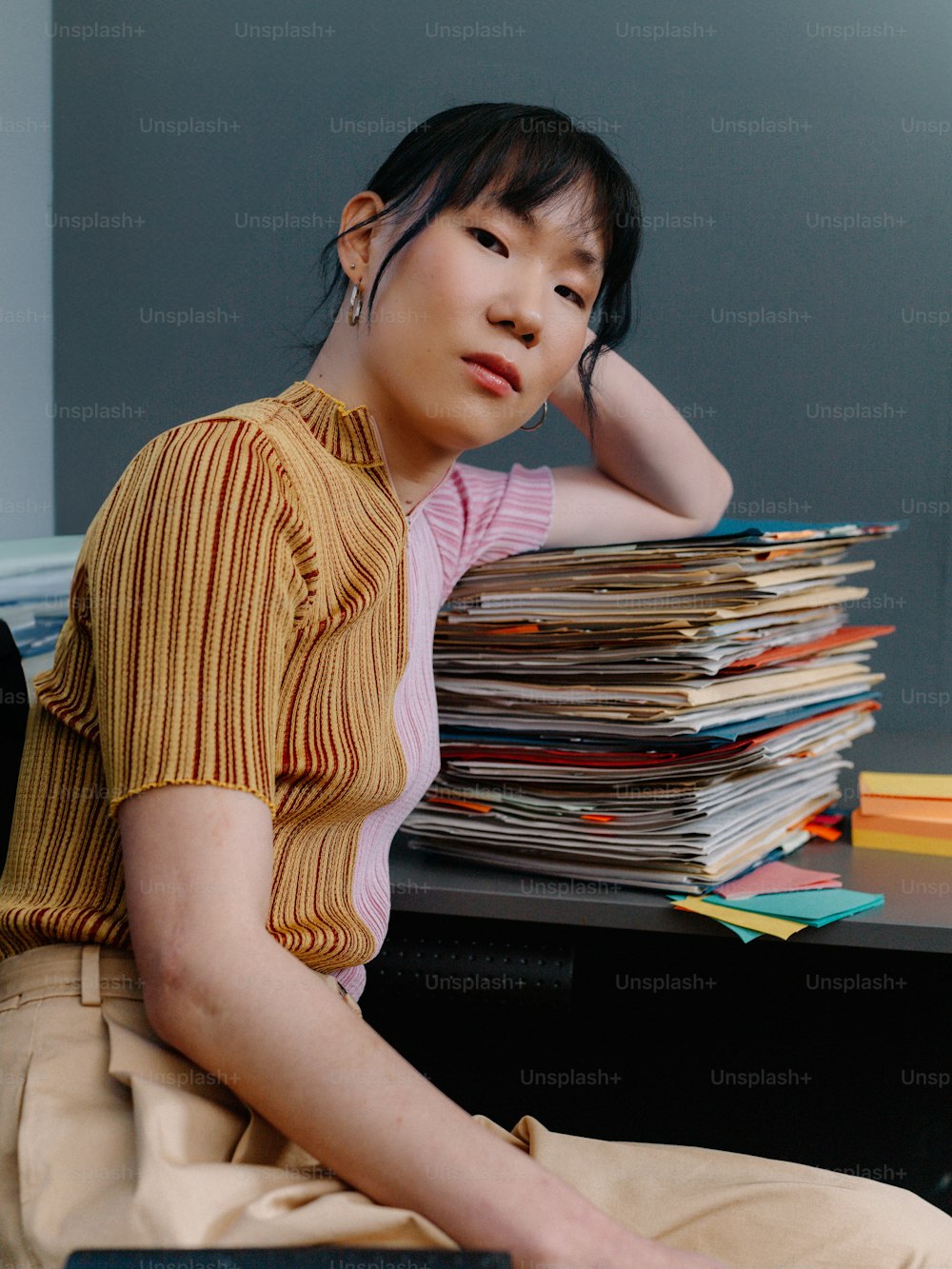 a woman sitting in front of a stack of papers