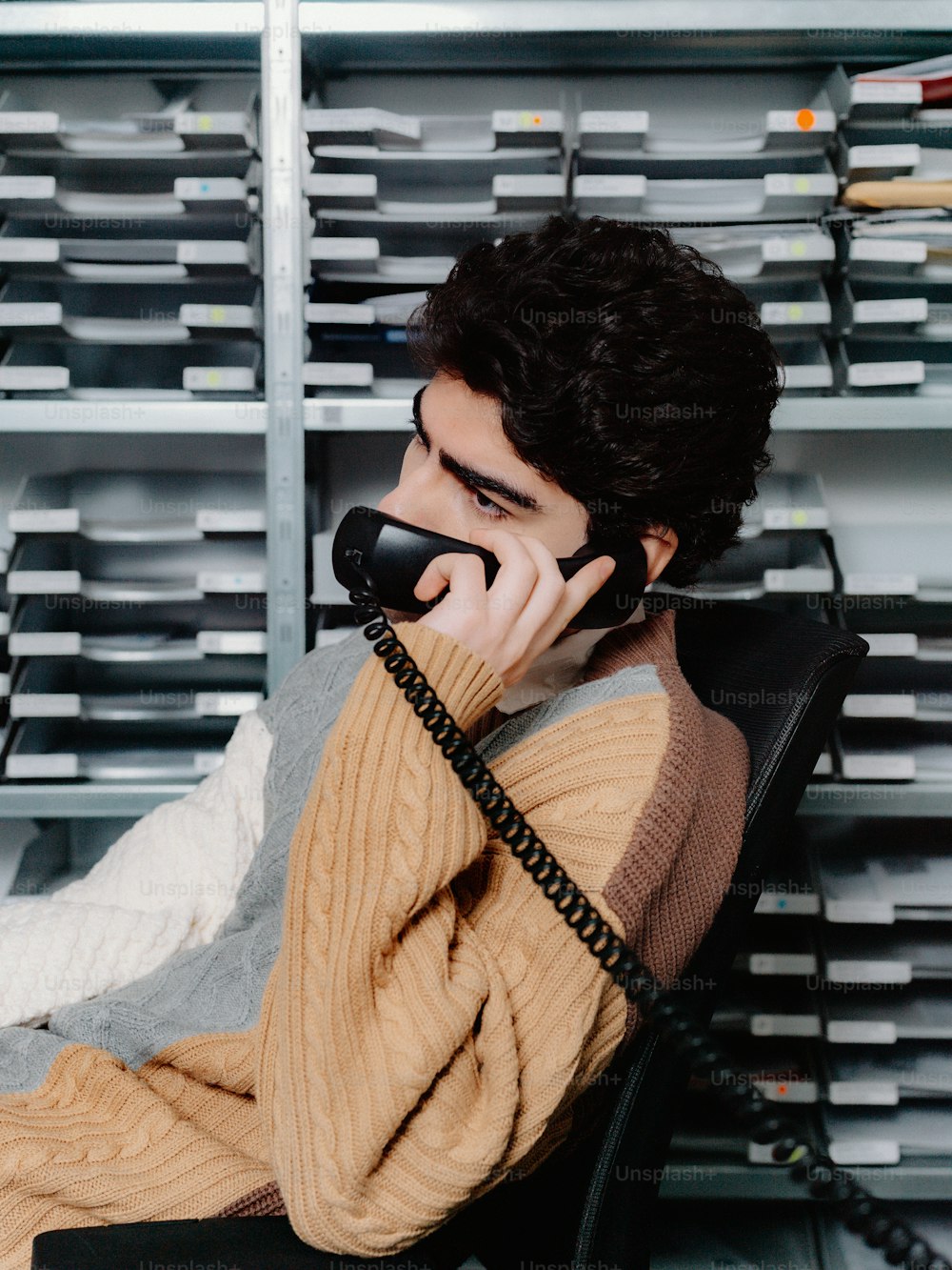 a man sitting in a chair talking on a telephone