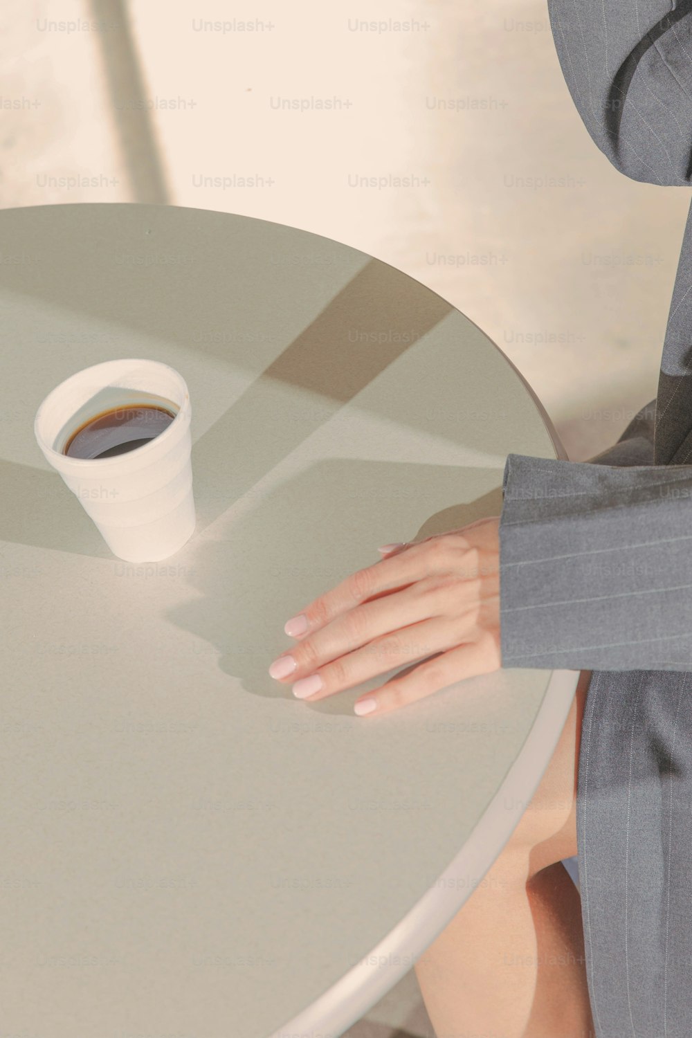 una persona sentada en una mesa con una taza de café