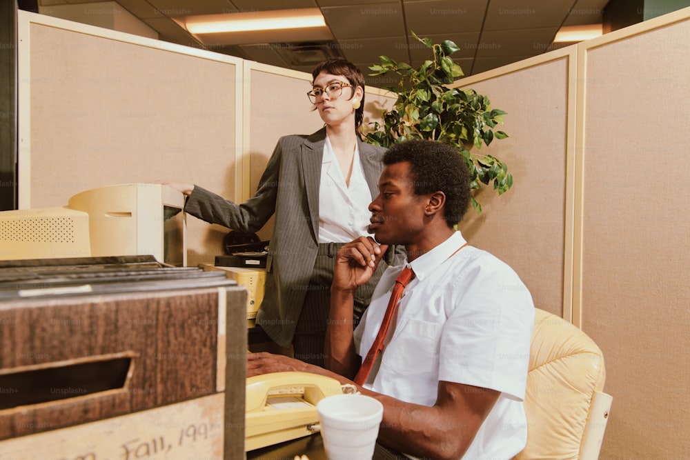 a man and a woman sitting in an office cubicle