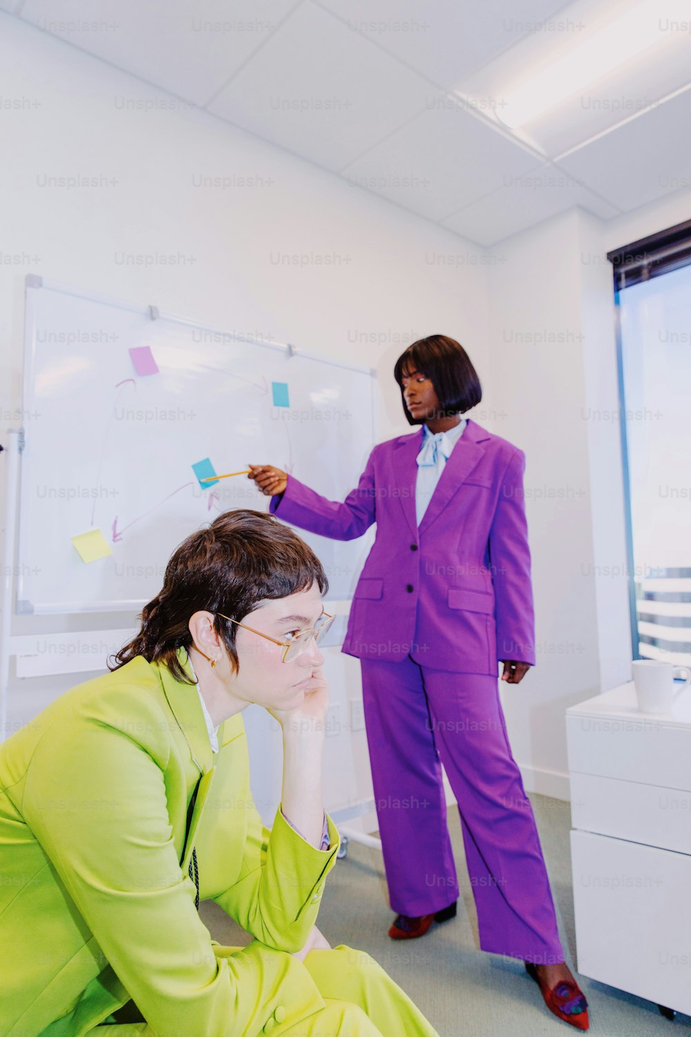 a woman in a purple suit standing next to a whiteboard
