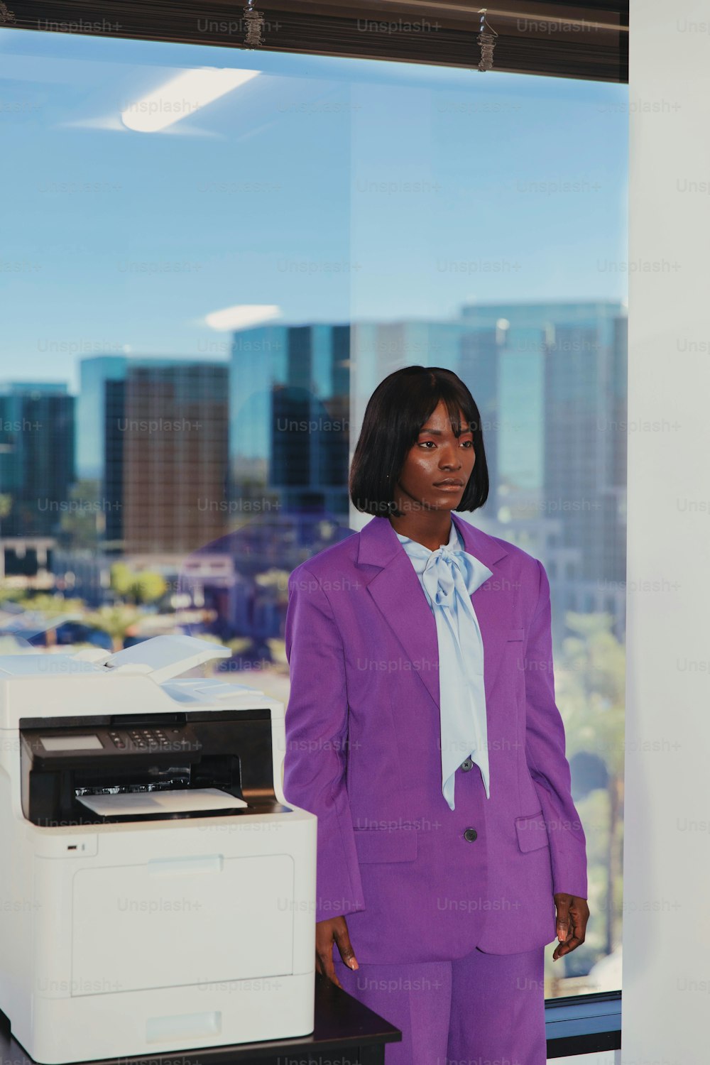 una mujer con un traje morado de pie junto a una impresora