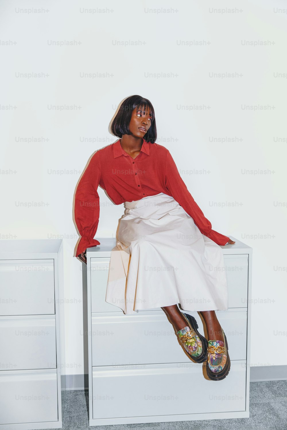 a woman sitting on top of a white dresser