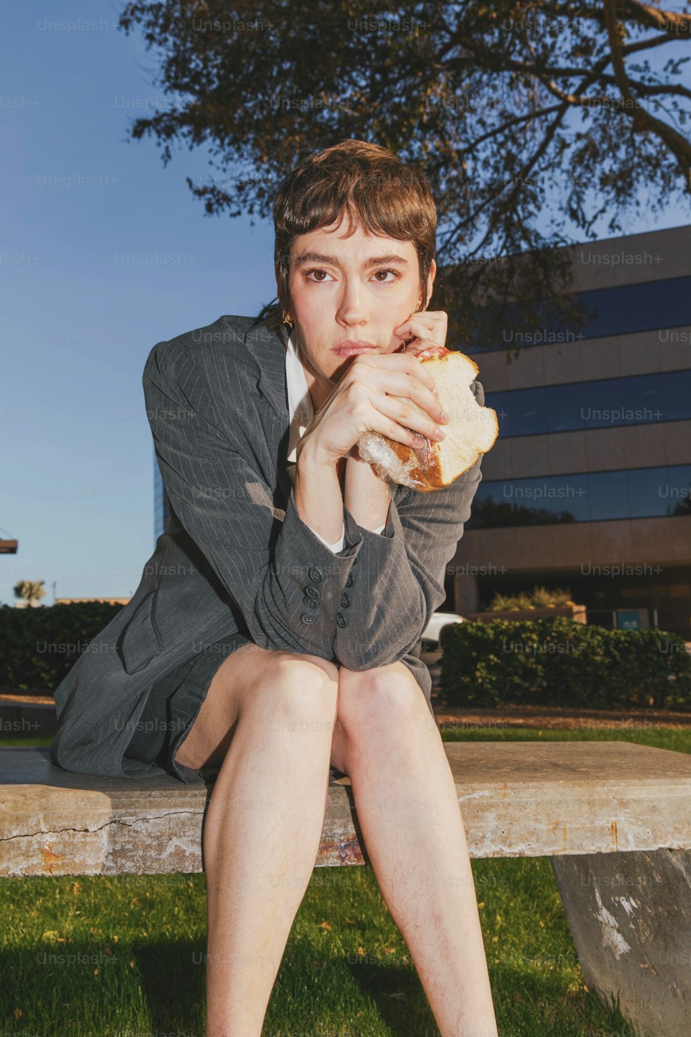 a woman sitting on a bench eating a sandwich