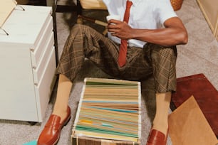 um homem sentado no chão ao lado de uma pilha de papéis