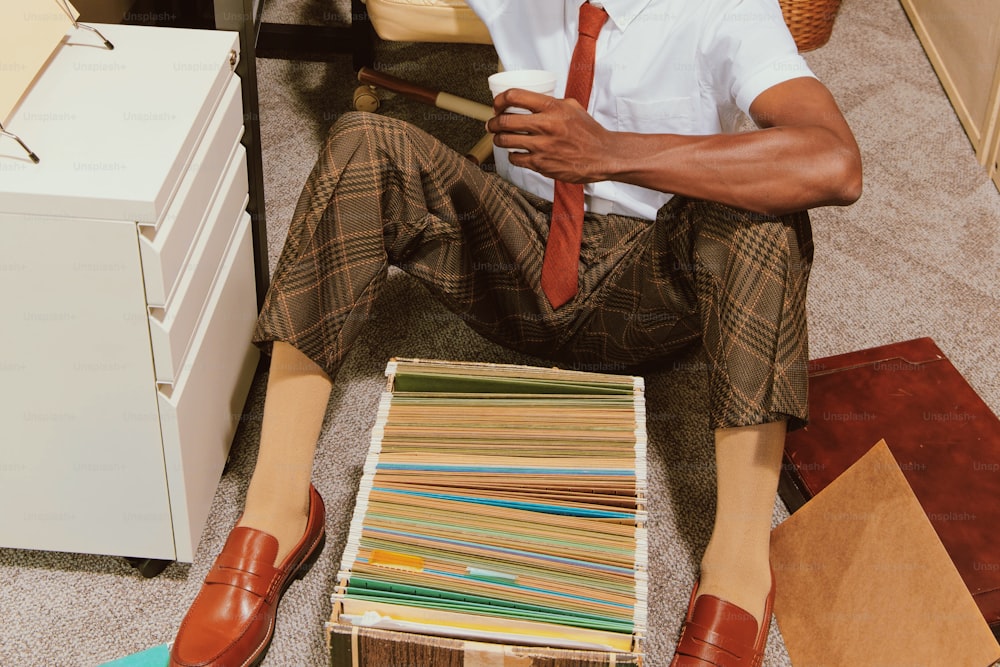 a man sitting on the floor next to a pile of papers